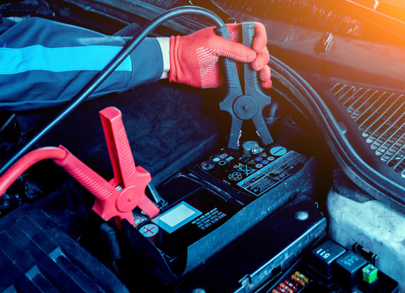 Kia-certified technician testing a car battery in the Cable Dahmer Kia service bay