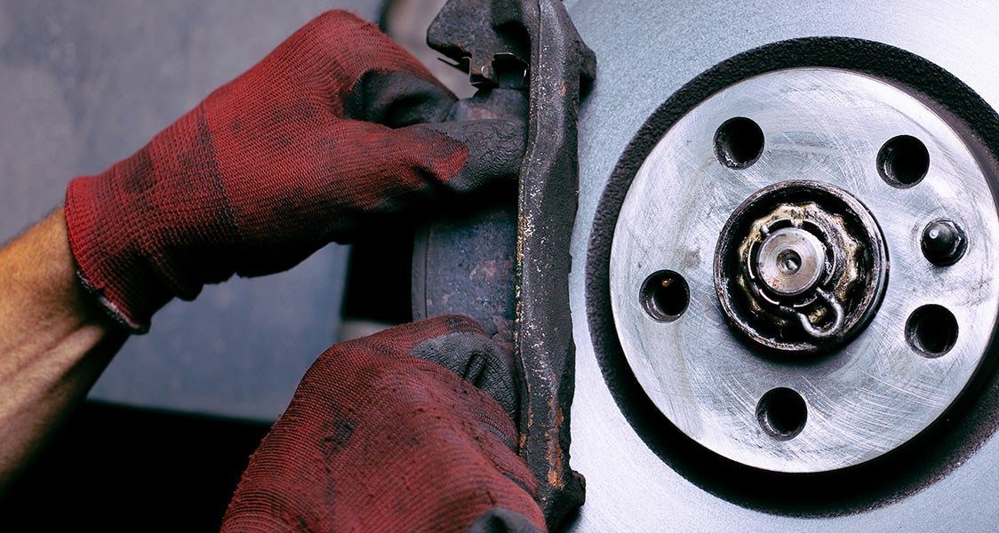 Technician performing a brake replacement on a Kia vehicle